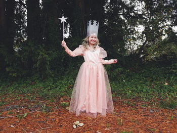 Full length of happy girl standing against tree