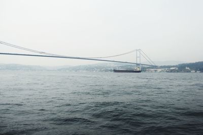 Suspension bridge over sea against clear sky