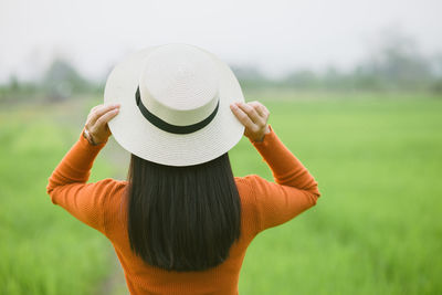 Rear view of woman wearing hat standing on field