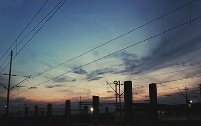 Low angle view of electricity pylon against cloudy sky