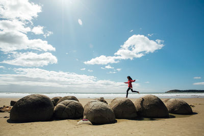 Man standing on rocks by sea against sky