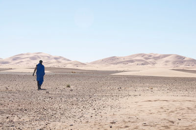 Man walking at desert against sky