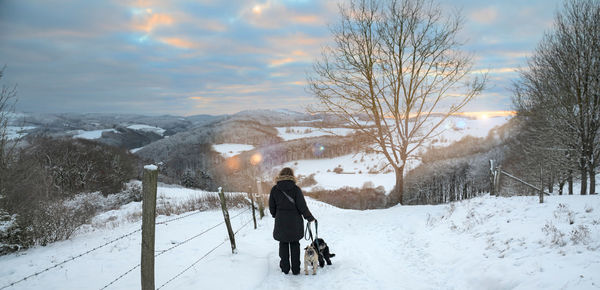 Rear view of people walking on snow covered landscape