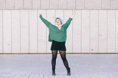 Full length of a young woman standing against wall