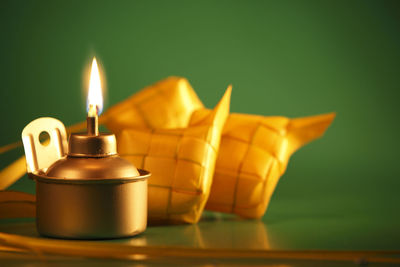 Close-up of ketupat with oil lamp on table