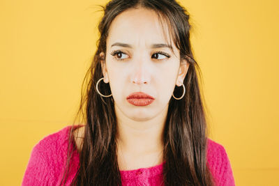 Portrait of young woman against yellow background