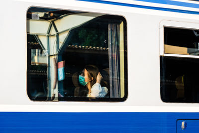 Low angle view of girl seen through train window