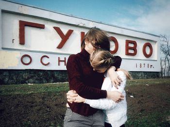 Young couple standing by text on wall