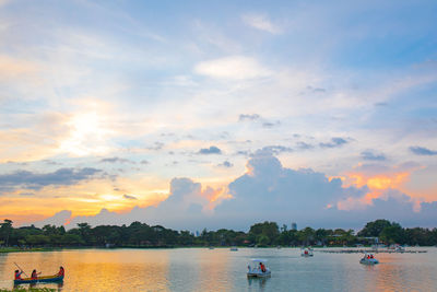 People on sea against sky during sunset