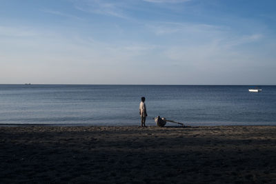 Man standing by boat moored in beach