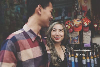 Portrait of smiling young couple standing against store
