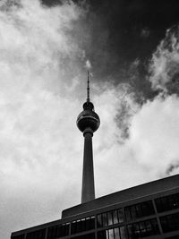 Low angle view of communications tower against cloudy sky