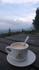 Coffee cup on table against sky