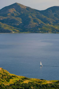 Sailboat on sea by mountains against sky