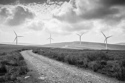 Wind turbines on field against sky