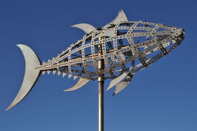 Low angle view of rollercoaster against clear blue sky