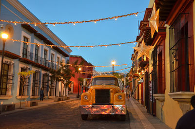 Illuminated street amidst buildings in city at night
