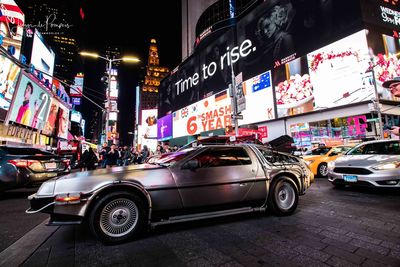 Cars on street against illuminated buildings in city at night