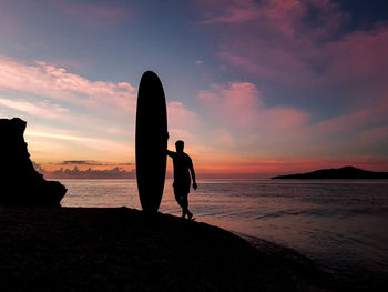 Silhouette people on beach against sky during sunset