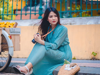 Portrait of young woman holding ice cream sitting outdoors