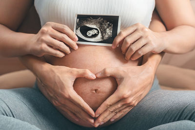 Midsection of woman holding heart shape