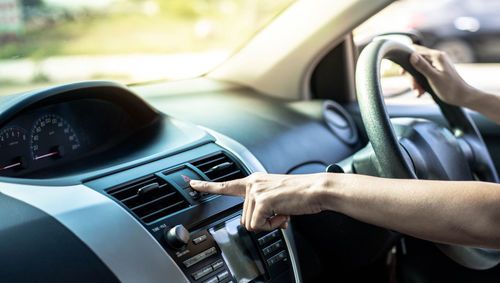 Cropped hand pressing push button in car