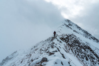 Person on snowcapped mountain against sky