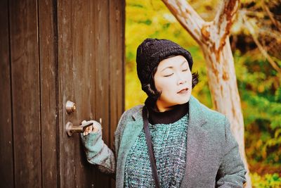 Woman in warm clothing standing by wooden door