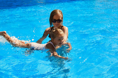 High angle view of mother and daughter swimming in pool