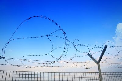 Low angle view of barbed wire against sky