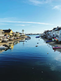 Sailboats moored in city by sea against sky