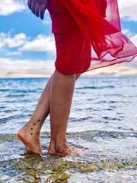 Low section of woman standing at beach