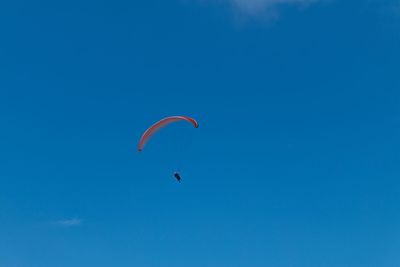 Low angle view of paragliding against blue sky