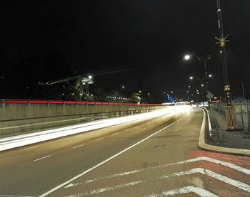 Illuminated road against sky at night