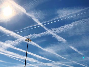 Low angle view of vapor trail against blue sky on sunny day