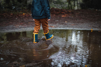 Low section of boy standing in puddle