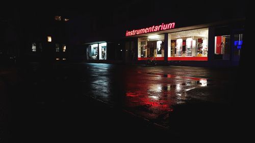 Wet illuminated street in city at night
