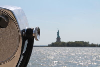 View of the statue of liberty with binoculars in the foreground.