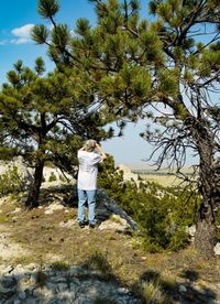 Rear view of man standing by tree against sky