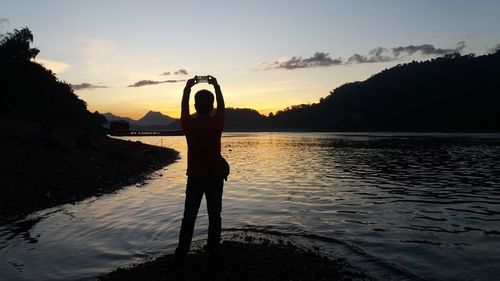 Silhouette man standing at beach against sky during sunset