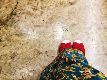 Low section of woman wearing dress and shoes on tiled floor