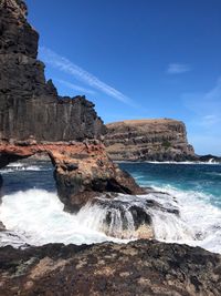 Scenic view of rocks on beach against blue sky