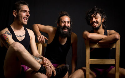 Happy friend sitting on chair against black background