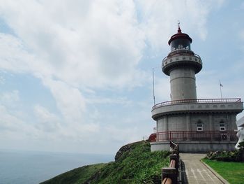 Lighthouse by sea against sky