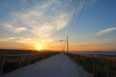 Road amidst land against sky during sunset