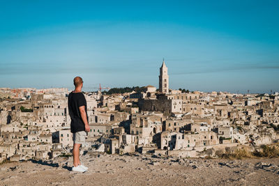 Rear view of man looking at buildings in city