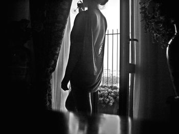 Rear view of a young woman standing on wooden floor