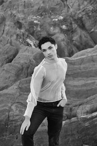 Young male with  androgynous look shot outdoor in black and white with rocks in background.