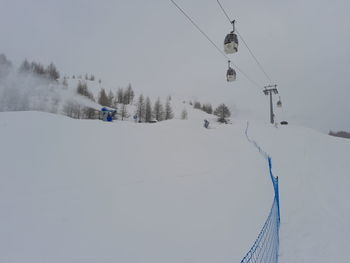 Close up of ski lift durino a snowfall with snow cannons belinda it ski on snow covered landscape