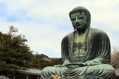 Low angle view of statue against trees against sky